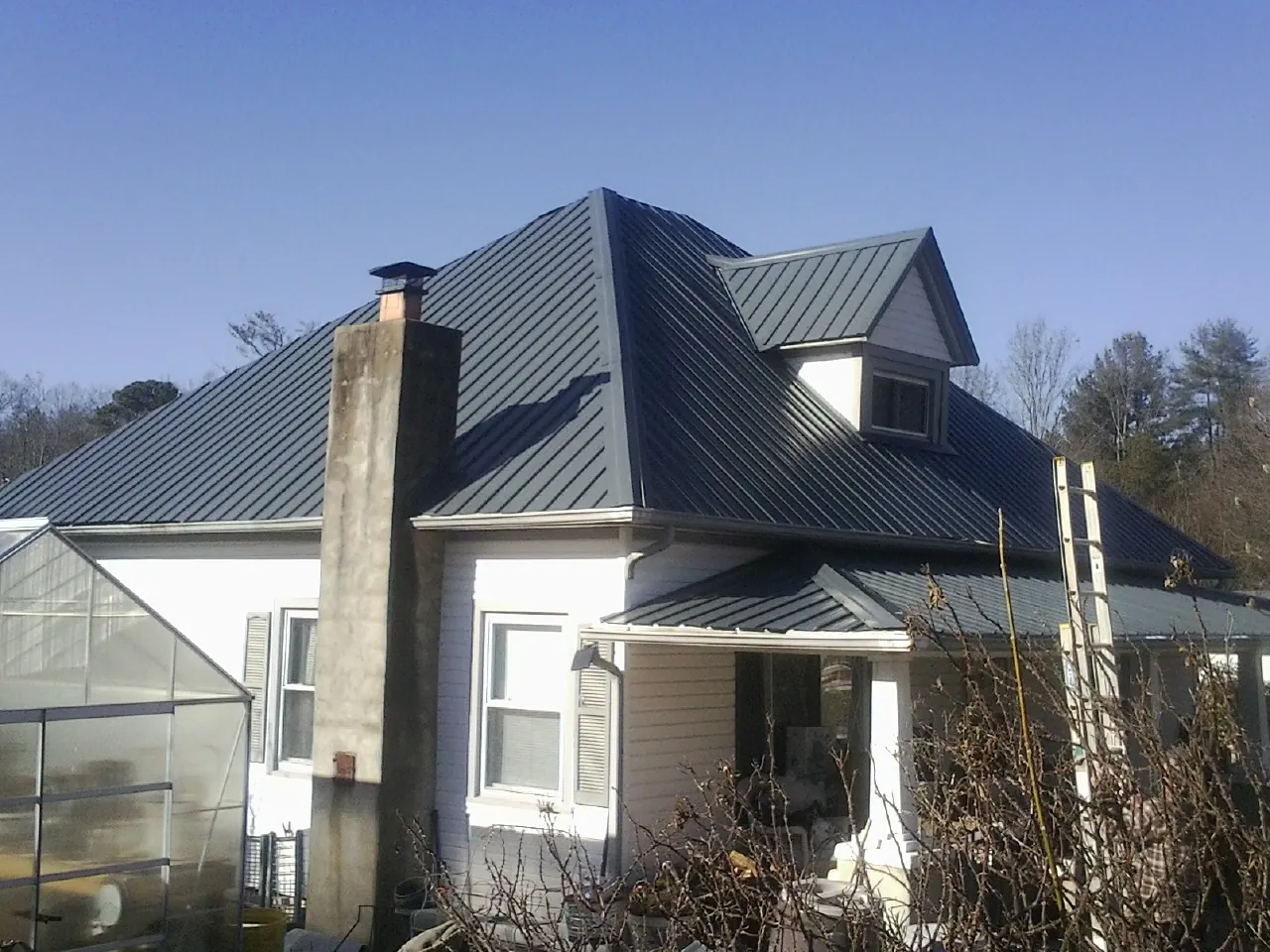 Dark blue standing seam metal roof on a white farmhouse with dormer — Slate & Tile Roof Repair by Roofing Brothers in Oak Brook