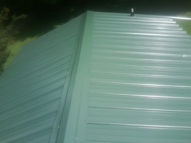 New green metal panels meeting at the ridge of a roof — Flat Roof Repair work by our crew in Oak Brook