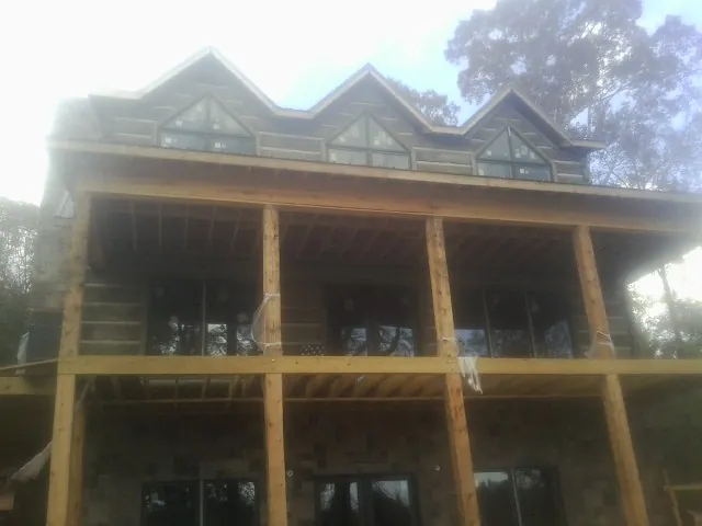 Dormers and porch framing on a large log home under construction — Roof Coating work by our crew in Oak Brook