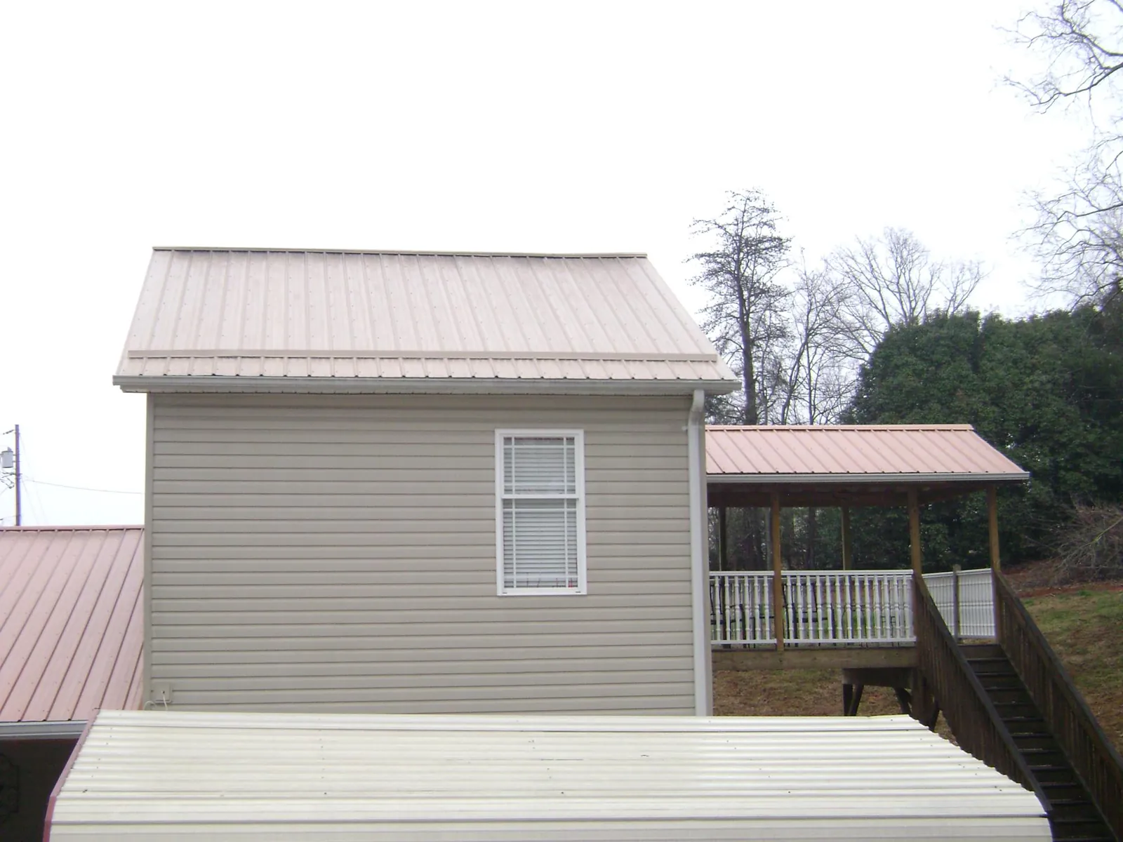 Tan metal roofs on a two story addition and attached porch, from a Roof Replacement job in Oak Brook