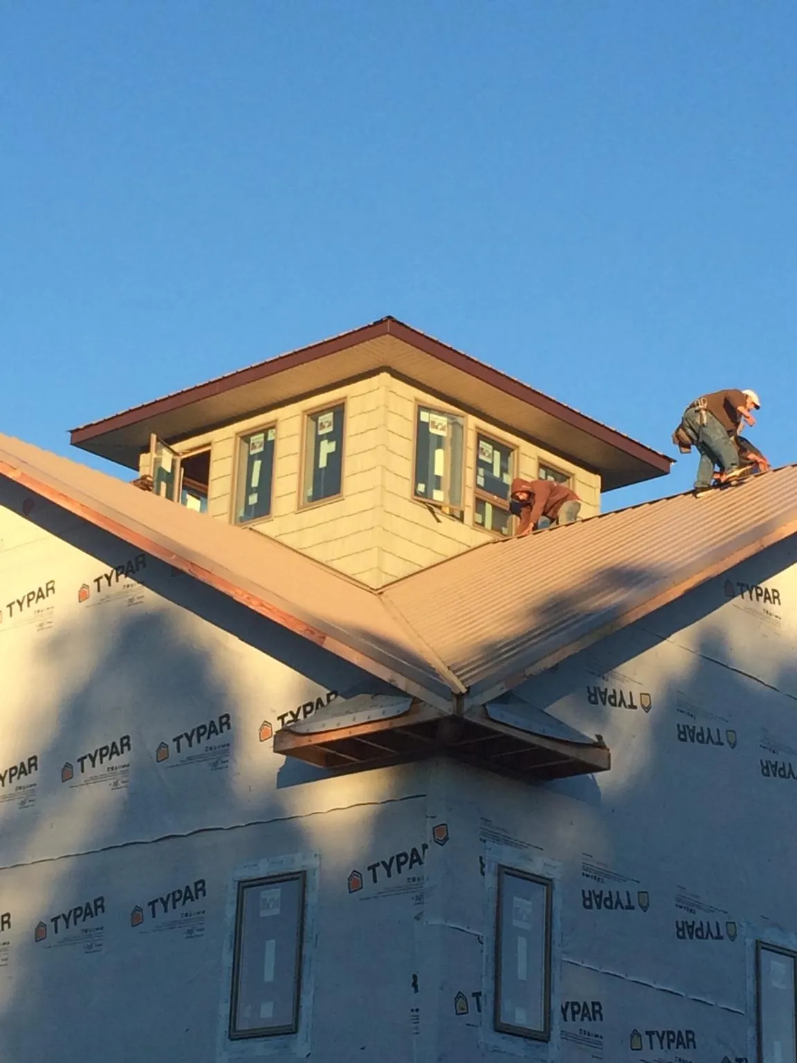 Roofers working around a rooftop cupola on a new metal roof at sunset — Roof Waterproofing in Oak Brook by Roofing Brothers